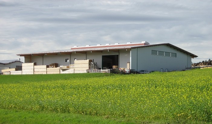 1200 qm große Halle von außen mit Bretterpaketen auf dem Außenplatz